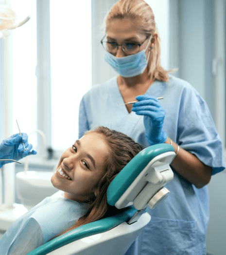 a girl smiles as she sits in the dentists chair